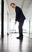 Businessman putting golf ball in office