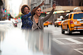 Women hailing taxi on city street