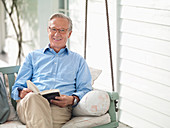 Man reading book on porch swing