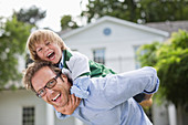 Man carrying son piggyback outdoors