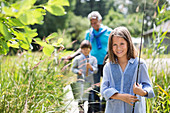 Girl carrying fishing rod in tall grass