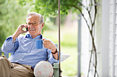 Man talking on cell phone in porch swing