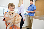 Owner holding cat in vet's surgery