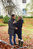 Smiling couple standing in autumn leaves