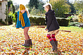 Girls playing together in autumn leaves