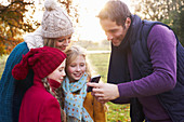 Family using cell phone together outdoors