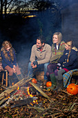 Family relaxing around campfire at night