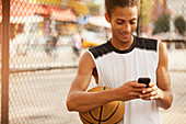 Man using cell phone on basketball court