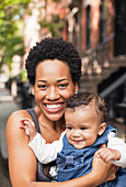 Mother holding baby on city street