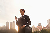 Businessman using cell phone in park
