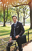 Businessman sitting on bicycle in park