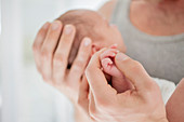 Mother cradling newborn baby's hand