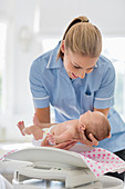 Nurse weighing newborn baby