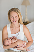 Mother cradling newborn baby on bed