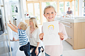 Girl showing off drawing in kitchen