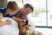 Father and son petting dog on sofa