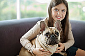 Girl relaxing dog on sofa