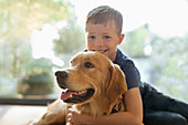 Smiling boy hugging dog indoors