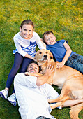 Family relaxing with dog on lawn