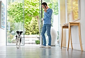 Dog running past man in kitchen