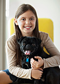 Smiling girl holding dog indoors