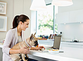 Woman using laptop with dog on lap