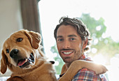 Smiling man petting dog indoors