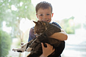 Smiling boy holding cat indoors