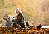 Older couple sitting in autumn leaves