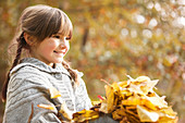 Smiling girl playing in autumn leaves