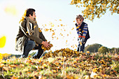 Father and son playing in autumn leaves
