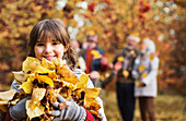 Girl playing with autumn leaves in park