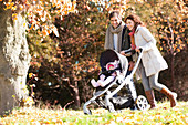 Couple pushing baby in stroller in park