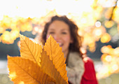 Woman holding autumn leaves in park