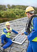 Workers installing solar panel on roof