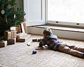 Boy playing with trains by Christmas tree