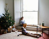 Children relaxing by Christmas tree