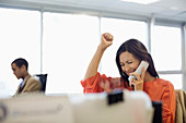 Businesswoman cheering at desk in office