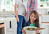 Girl holding bowl of salad in kitchen