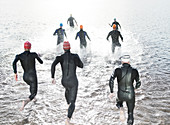 Triathletes in wetsuits running