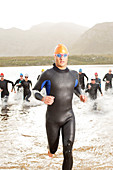 Triathletes in wetsuit running in waves