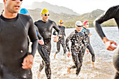 Triathletes in wetsuits walking in waves