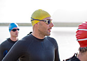 Triathletes in wetsuits standing on beach