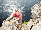 Climber scaling coastal cliff