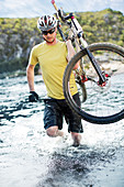Man carrying mountain bike in river