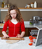 Girl rolling dough in kitchen