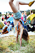 Woman doing handstand outside tents