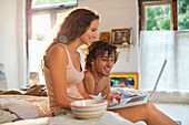 Couple using laptop together in bed