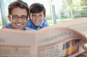 Father and son reading newspaper together