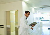 Doctor reading medical chart hallway